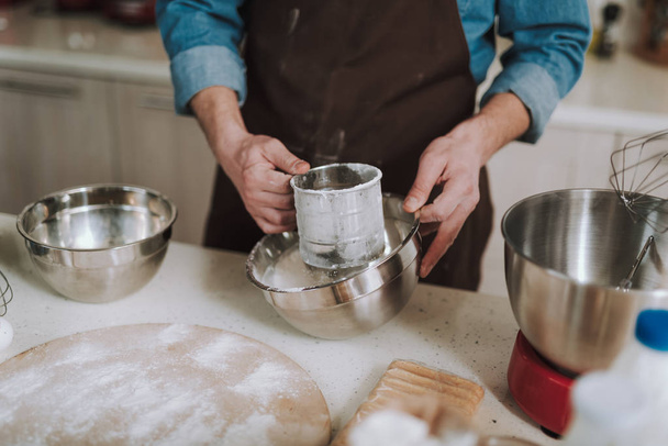 Hands of person sifting flour into deep bowl - Foto, Bild