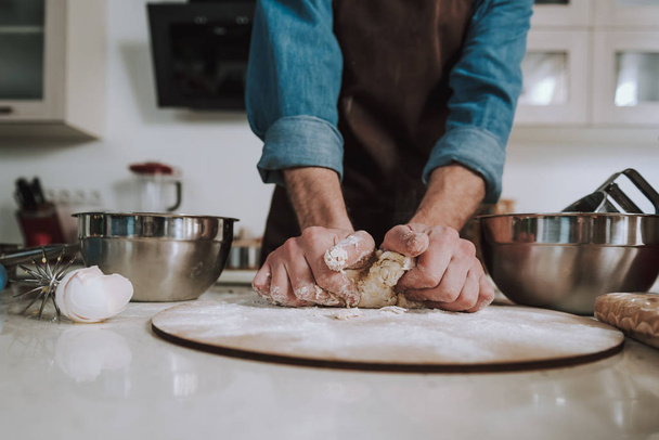 Strong hands of man kneading dough on the wooden cutting board - Φωτογραφία, εικόνα