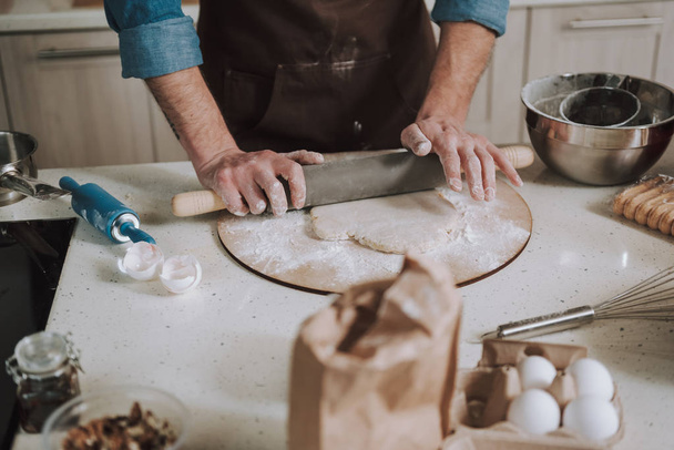 Hands of man pressing the rolling pin while rolling dough - Foto, imagen