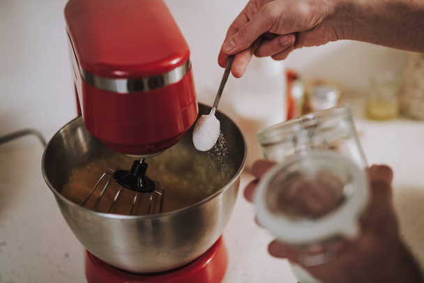 Hand sifting sugar into the bowl of mixer - Photo, Image