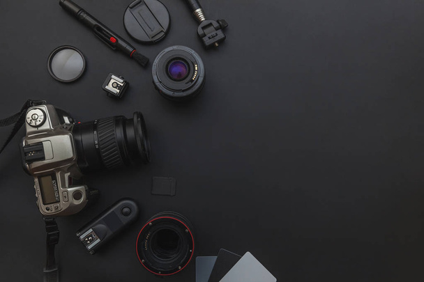 デジタル一眼レフカメラシステム、カメラのクリーニングキット、暗い黒のテーブルの背景にレンズとカメラのアクセサリーとカメラマンの職場 - 写真・画像