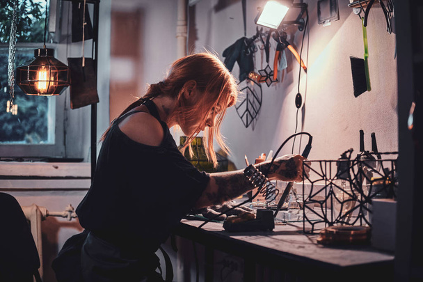Diligente donna sta lavorando al proprio progetto in laboratorio di vetro
. - Foto, immagini
