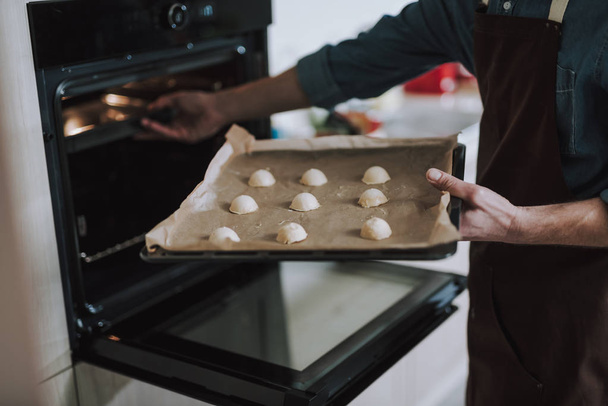 Person holding sheet pan and putting it into the oven - Fotografie, Obrázek