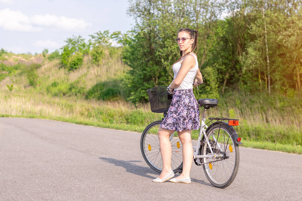 Actief leven. Een vrouw met een fiets geniet van het uitzicht in het zomer bos. Lifestyle concept voor fietsen en ecologie. - Foto, afbeelding