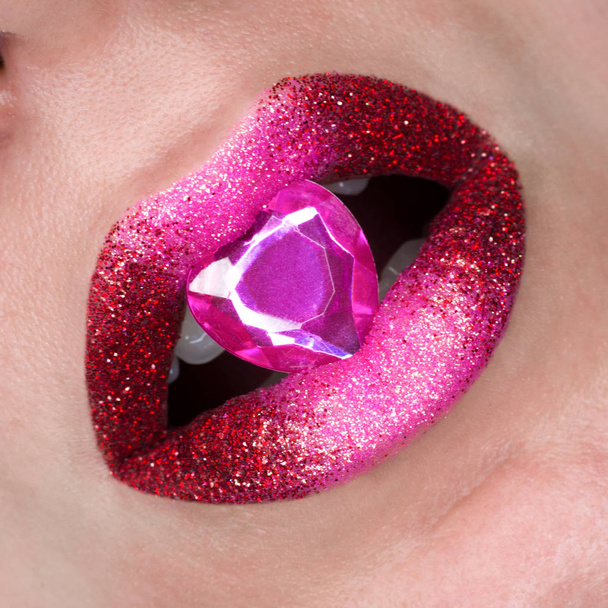 Rood roze lippen bedekt met sparkles en met diamong. Mooie vrouw met rood roze lippenstift op haar lippen, open mond - Foto, afbeelding