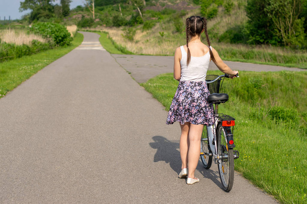 活発な生活。自転車を持つ女性が夏の森の景色を楽しんでいます。自転車とエコロジーライフスタイルのコンセプト. - 写真・画像