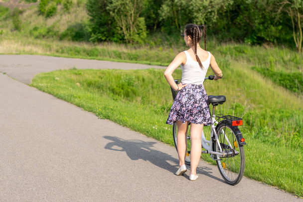 Активне життя. Жінка з велосипедом насолоджується видом на літній ліс. Концепція велосипедного та екологічного способу життя
. - Фото, зображення
