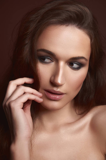 Beautiful young lady with evening makeup posing against brown background - Φωτογραφία, εικόνα