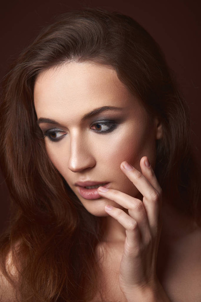Gorgeous young woman with evening makeup holding hand near face - Foto, afbeelding
