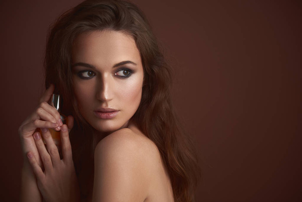 Attractive young woman with smokey eyes makeup holding perfume - Foto, Bild