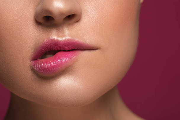 Woman biting her lip isolated on the maroon background - Foto, Imagem