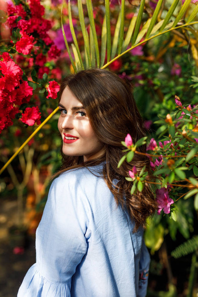 portrait of a young beautiful woman in a blue dress in a beautiful botanic garden with flowers - Foto, Imagem