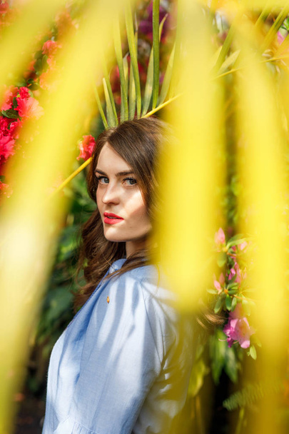 portrait of a young beautiful woman in a blue dress in a beautiful botanic garden with flowers - Fotó, kép