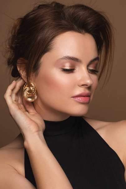 Gorgeous woman in black dress and with golden earrings - Foto, imagen