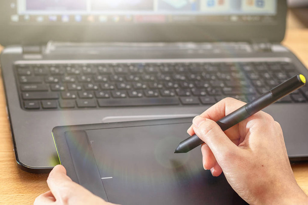 Kuvittaja käyttää grafiikkatablettia. Naisten korjaajat kädet kannettavan tietokoneen ja piirustus tabletti
 - Valokuva, kuva