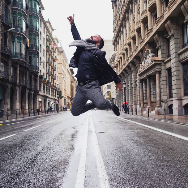 a young man jumps in Via Laietana, Barcelona, in a winter and rainy day - Fotoğraf, Görsel