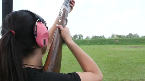 jovem menina bonita dispara um alvo voador em uma faixa de tiro aberto, tiro armadilha
 - Filmagem, Vídeo