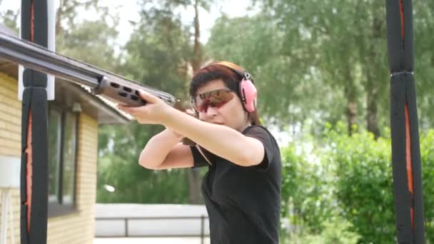 jong mooi meisje schiet een vliegend doel op een open schietbaan, val schieten - Video