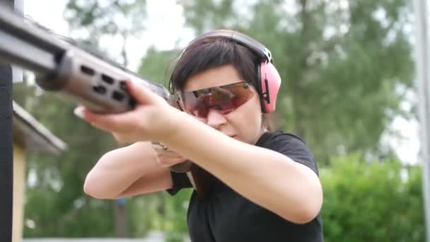 jong mooi meisje schiet een vliegend doel op een open schietbaan, val schieten - Video
