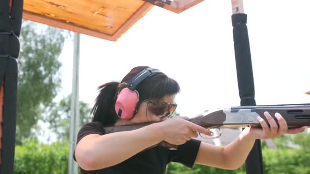 fiatal gyönyörű lány lő egy repülő célpont nyílt lőtéren, csapda lövés - Felvétel, videó