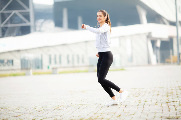 Mujer de fitness haciendo ejercicio de pie en un fondo de estadio
 - Foto, Imagen