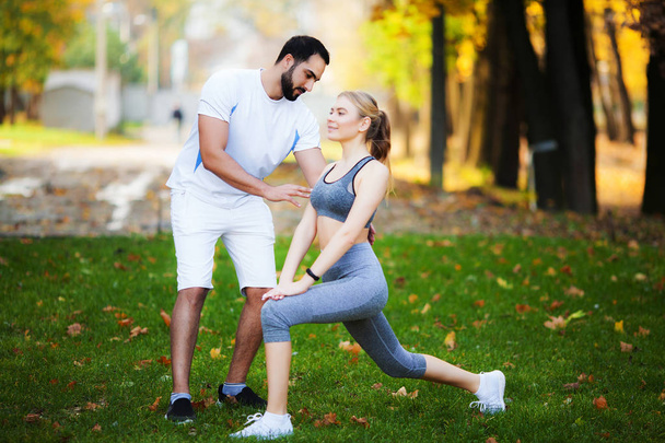 Fitness. Entrenador personal toma notas mientras la mujer hace ejercicio al aire libre
 - Foto, Imagen