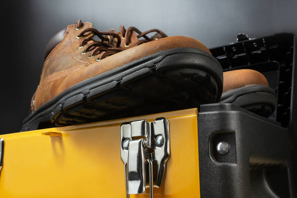 Working boots on yellow toolbox. - 写真・画像