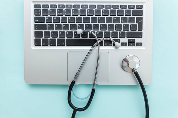 Stethoskop-Tastatur-Laptop isoliert auf blauem Hintergrund. Moderne medizinische Informationstechnologie und Software bringen das Konzept voran. Computer und Gadget Diagnose und Reparatur - Foto, Bild