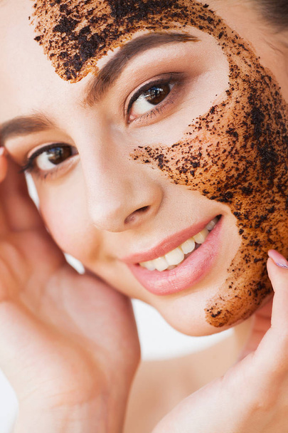 Pleťový peeling kůže. Usmívající se dívka použití křoviny kávy masky na pleť - Fotografie, Obrázek