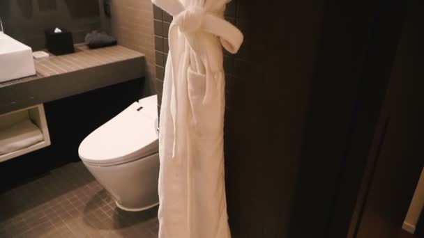 Valkoinen kylpytakki roikkuu kylpyhuoneessa
 - Materiaali, video