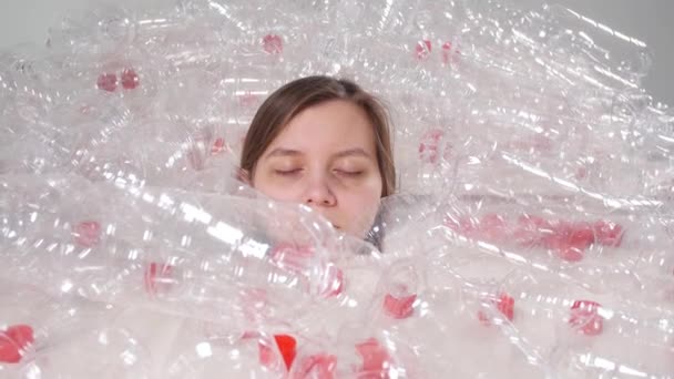 Dehydrated sick woman is lying in a pile of plastic bottles. Environmental pollution problem. Stop nature garbage environment protection concept - Footage, Video