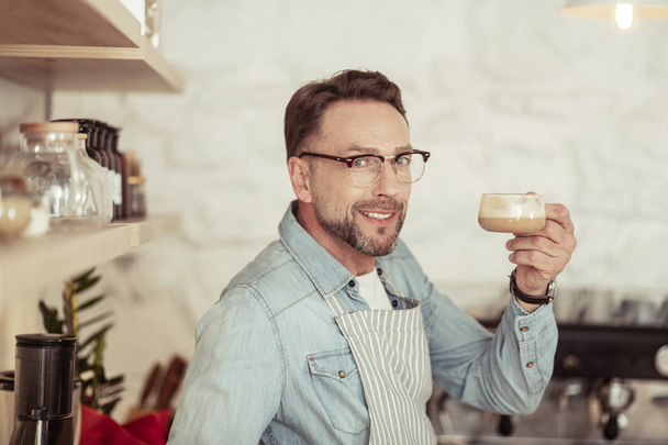 Smiling man holding up his cup of coffee. - Foto, Bild