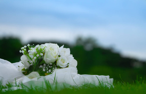 Λευκά τριαντάφυλλα γαμήλια ανθοδέσμη τοποθετούνται σε πράσινο γκαζόν στον κήπο. - Φωτογραφία, εικόνα