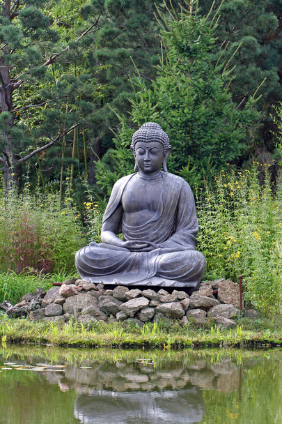 Estatua de Buda meditando frente al lago, en la naturaleza
 - Foto, imagen