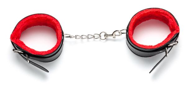 Бондаж, БДСМ чорні шкіряні наручники з червоним хутром всередині, на ланцюзі. Сексуальні іграшки. Ізольовані на білому тлі
. - Фото, зображення