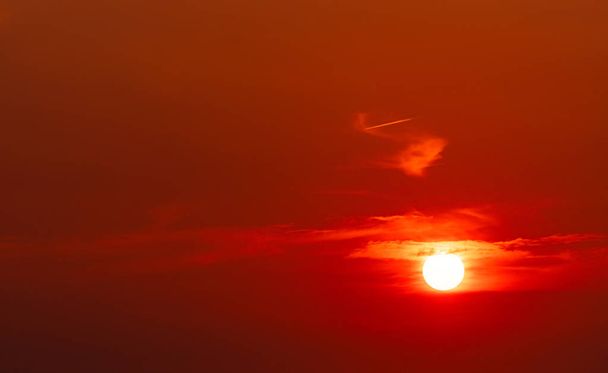 Gyönyörű vörös nap naplementekor. Vörös naplemente égen. A nap elhomályosítja néhány felhők naplementekor. Este nagy napsütés. Vérégbolt. Melegség és meleg időjárás. Drámai napfényt. Háttér a fenséges. - Fotó, kép