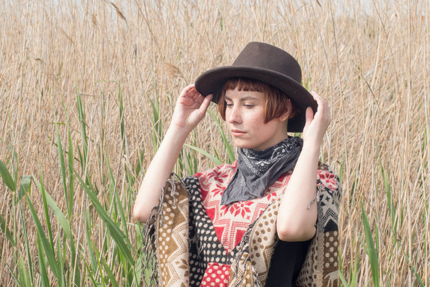 Jeune femme voyageuse en poncho et chapeau marche dans les champs et la ferme
 - Photo, image