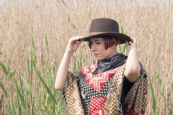 Jeune femme voyageuse en poncho et chapeau marche dans les champs et la ferme
 - Photo, image