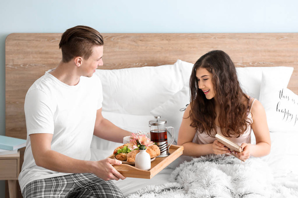Молода жінка отримує сніданок у ліжку від свого коханого чоловіка
 - Фото, зображення