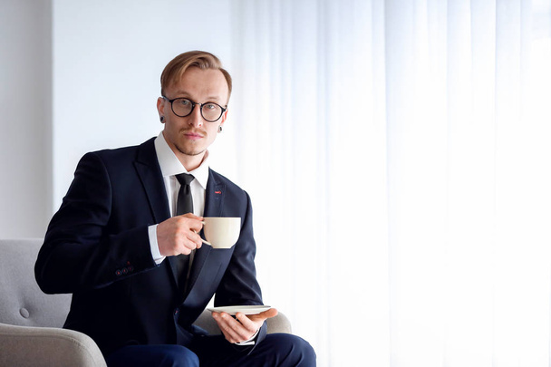 Όμορφος επιχειρηματίας που πίνει καφέ κοντά στο παράθυρο - Φωτογραφία, εικόνα