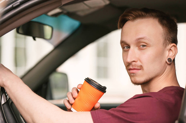 Handsome man drinking coffee in car - Photo, image