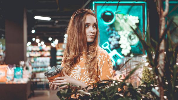Young woman buying flowers at a garden center - Foto, Bild