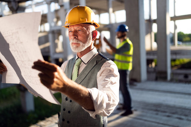 Инженер и менеджер строительной площадки, занимающийся чертежами и планами - Фото, изображение