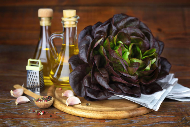 Cabeza de lechuga roja fresca, aceite y condimento en la mesa de madera
 - Foto, Imagen