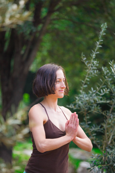 Eine Frau praktiziert Yoga im Hof eines Holzhauses. - Foto, Bild