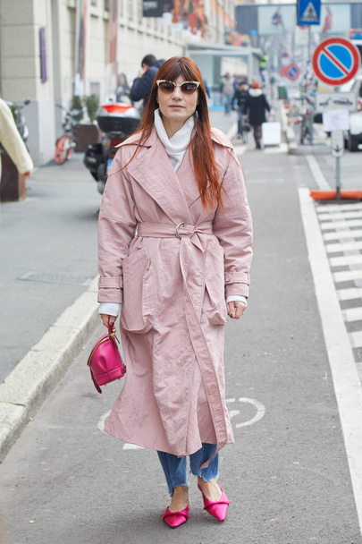Woman with pink trench coat and bag walking before fashion Albino Teodoro show, Milan Fashion Week street style on February 21, 2018 in Milan. - Фото, изображение