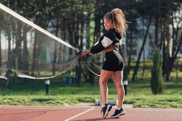 Młoda atrakcyjna kobieta pozuje na boisku do siatkówki - Zdjęcie, obraz