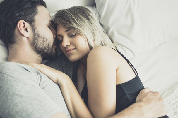 verliebtes glückliches Paar lächelt und umarmt sich auf dem Bett, - Foto, Bild