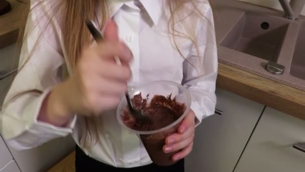 Mała dziewczynka z brudną twarzą jedzenia pudding czekoladowy - Materiał filmowy, wideo