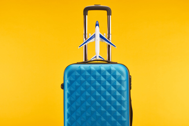 blue colorful travel bag with handle and toy plane isolated on yellow - Φωτογραφία, εικόνα